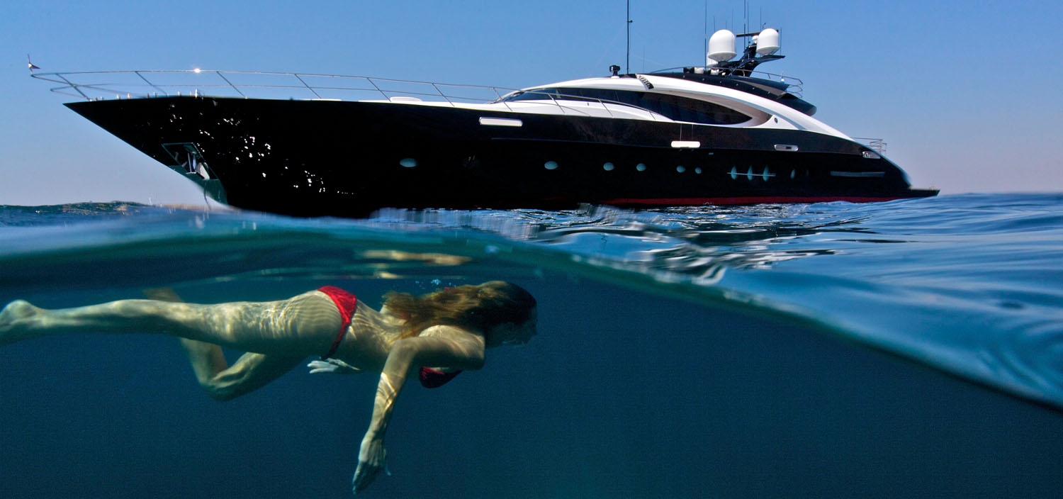 Active Tahiti superyacht charter as a woman swims under a luxury boat